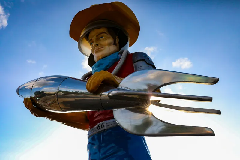A Route 66 space cowboy statue in Tulsa holding a giant fork and spoon